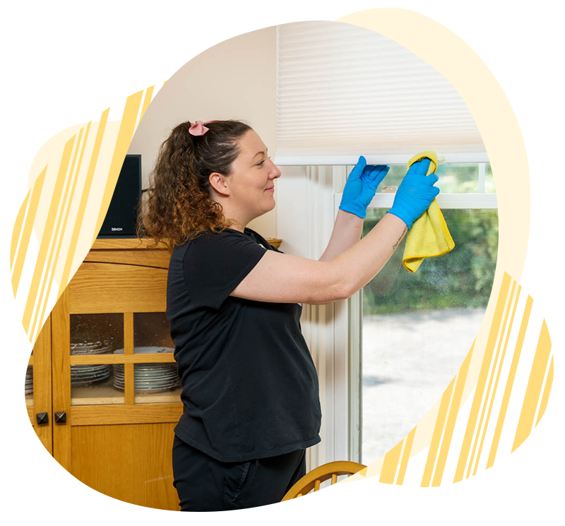 Belle Home cleaner polishing a window in an apartment